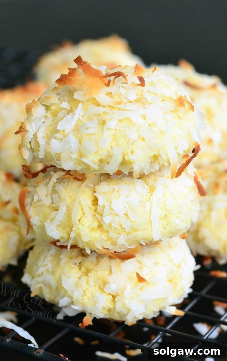 A stacked trio of Coconut Pudding Cookies on a cooling rack, showcasing their fluffy texture and enticing golden toasted coconut flakes, ready to be enjoyed.
