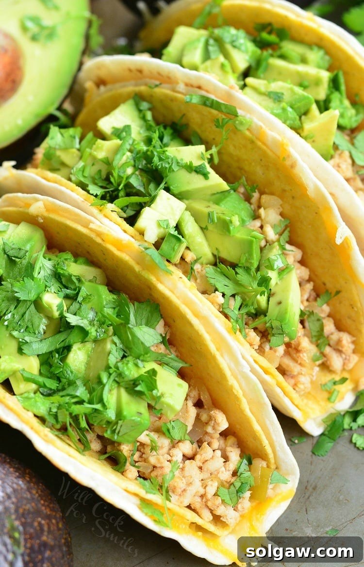 Top-down view of vibrant Avocado Turkey Tacos with ground turkey, fresh avocado slices, and chopped cilantro, nestled in a crispy hard shell