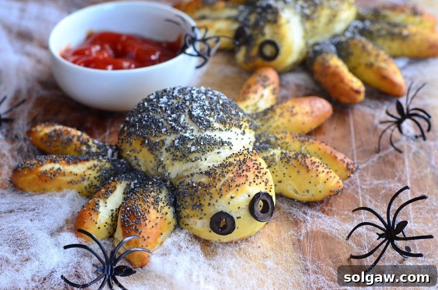 Pretzel Spiders displayed on a cutting board with a fake spider web, a bowl of red dipping sauce, and plastic spiders scattered around.