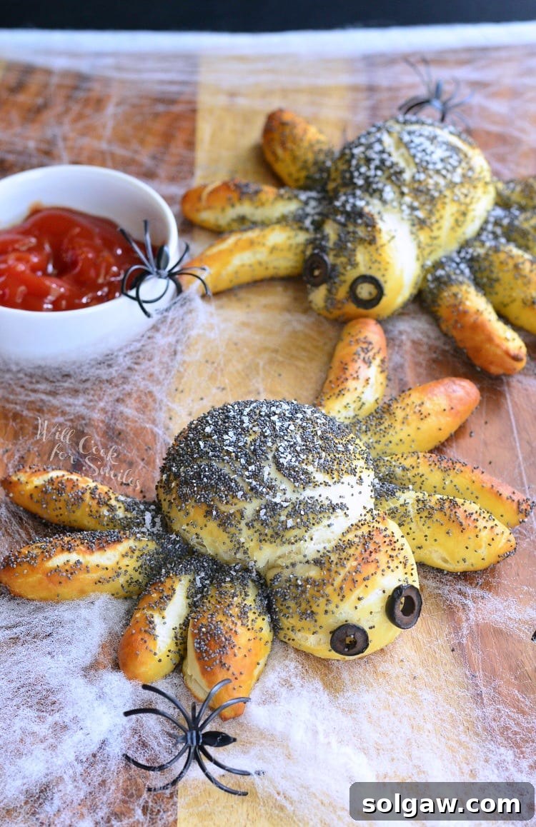 Pretzel Spiders with black olive eyes and red dipping sauce in a white bowl, surrounded by fake plastic spiders.