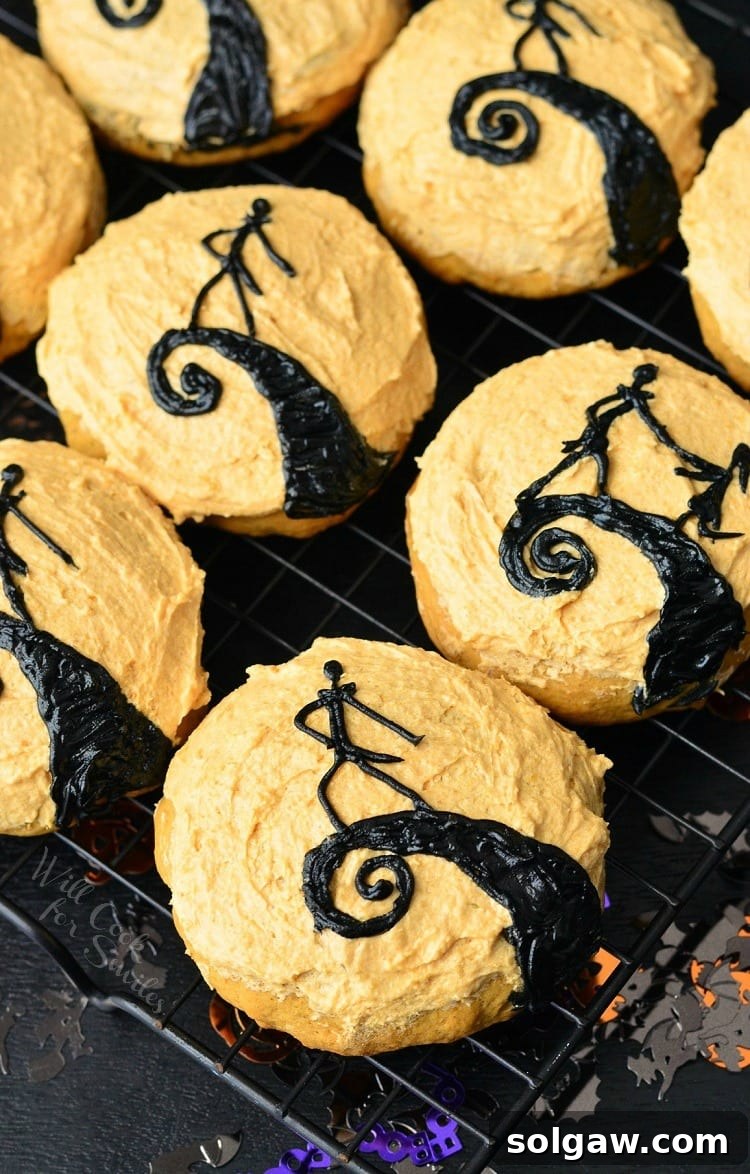 The Nightmare Before Christmas Pumpkin Cookies with orange frosting on a cooking rack.