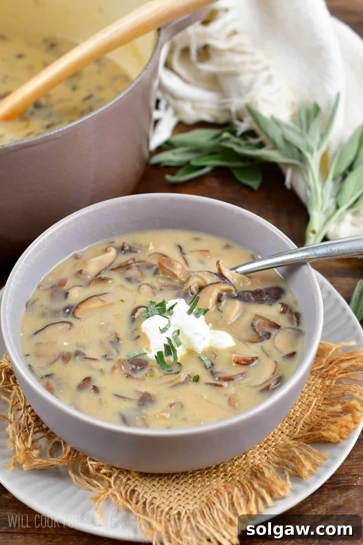 A close-up shot of creamy mushroom soup in a grey bowl, garnished with sour cream and a spoon, ready to be enjoyed.
