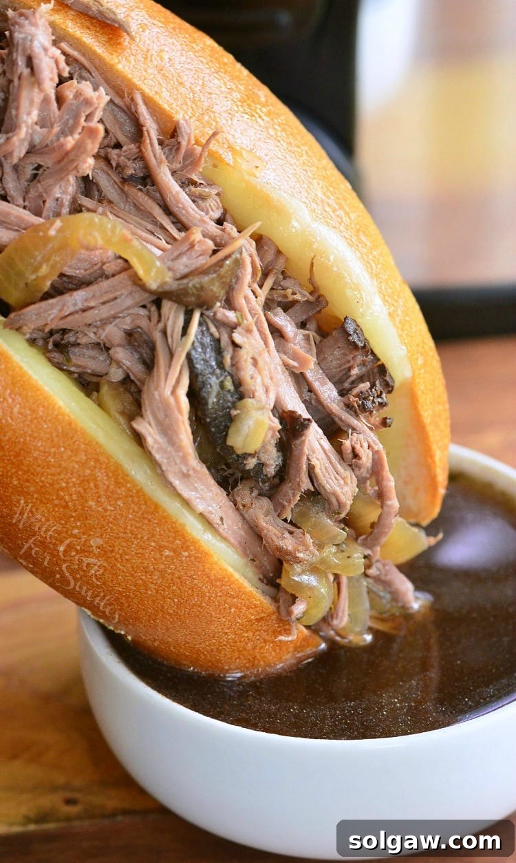 Mouthwatering Mushroom and Onion Italian Beef sub being dipped in savory au jus sauce