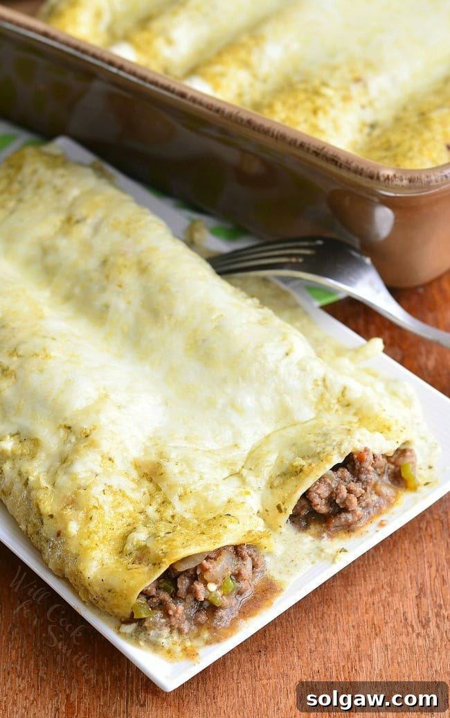Two vibrant Beef Enchiladas Verde on a white plate with a fork, alongside a casserole dish of more enchiladas.