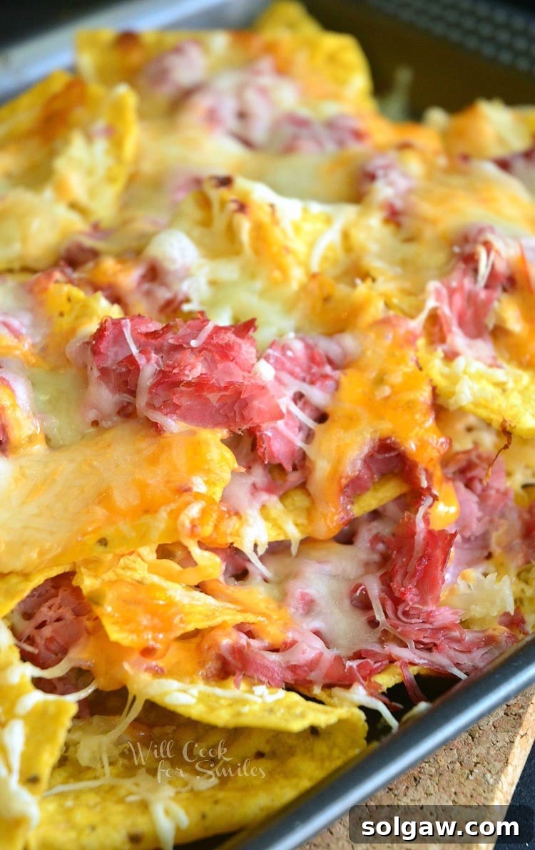 Tortilla chips, corn beef, and cheese on a baking sheet, creating delicious Reuben Nachos