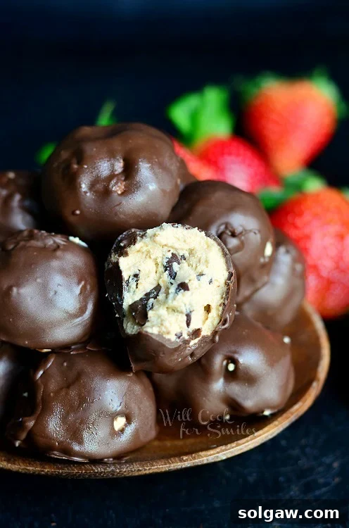 (No Bake) Chocolate Covered Peanut Butter Cheesecake Bites in a bowl with one with a bite out of it