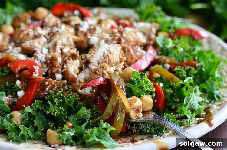White decorative bowl filled with balsamic chicken, veggies and chick pea salad as viewed close up.