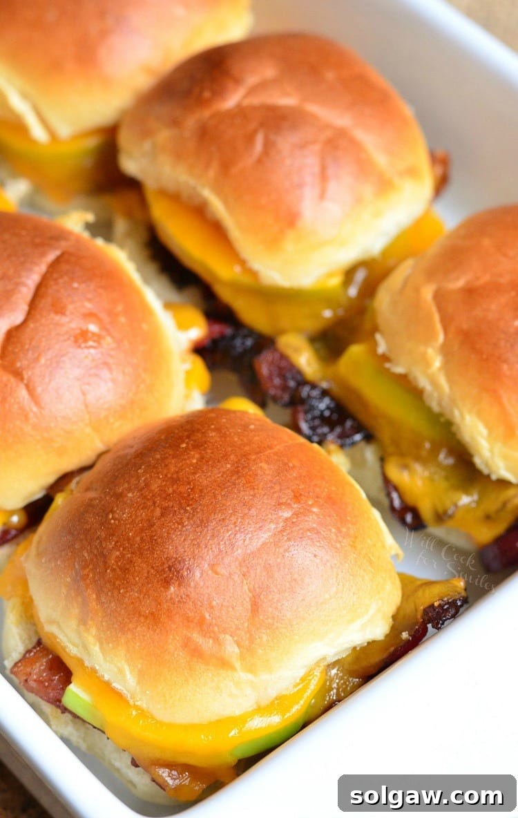 Delicious Apple Bacon Cheddar Baked Sliders arranged in a baking dish, ready to be served as a perfect party appetizer.