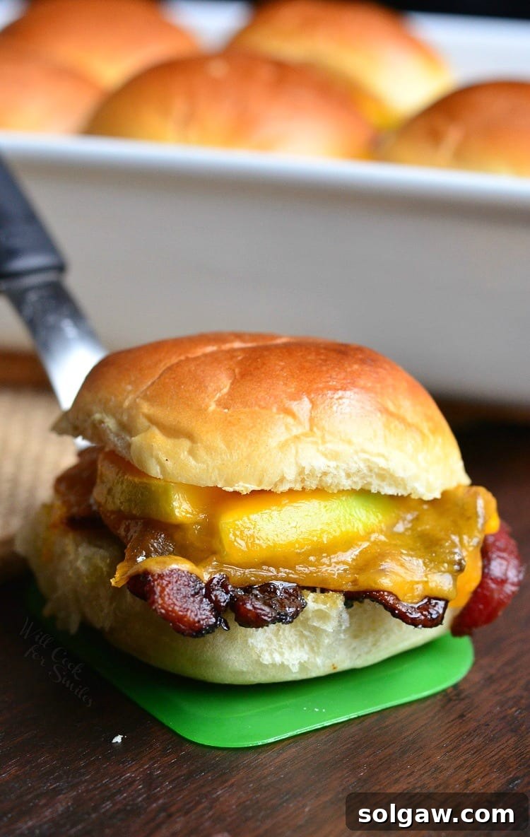 Apple Bacon Cheddar Baked Sliders on a green spatula, above a wooden cutting board.