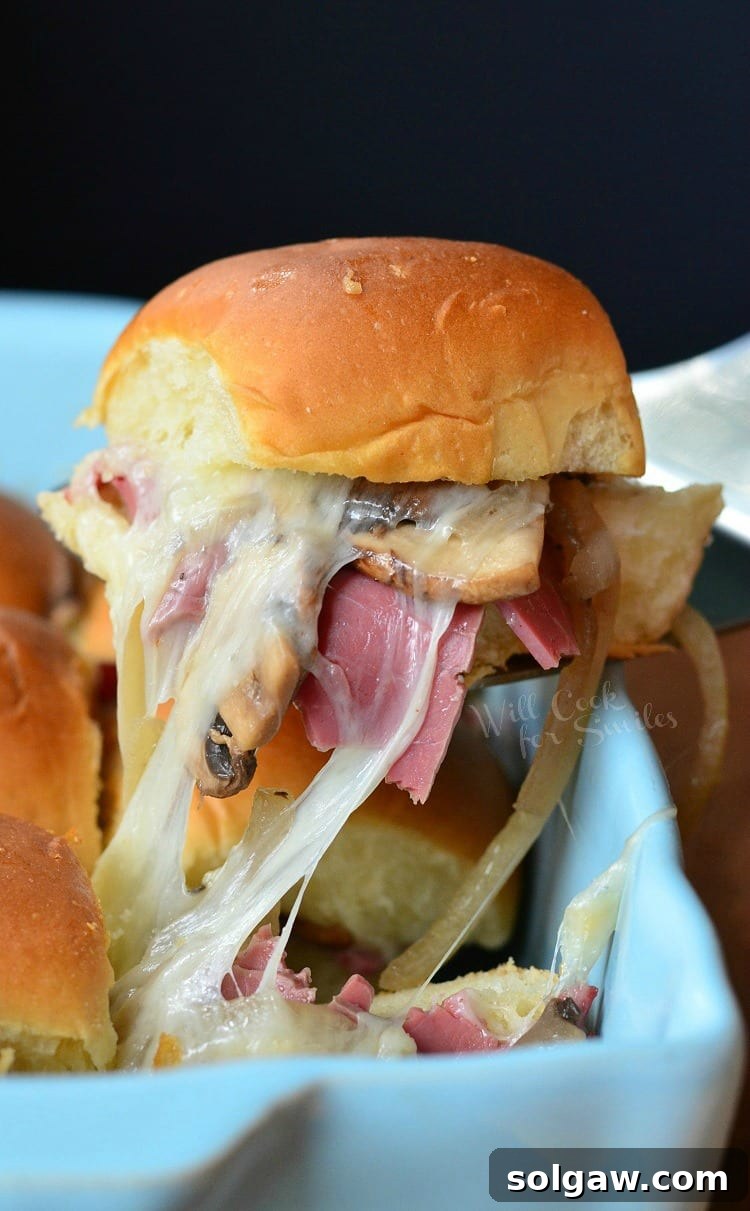 Baked Corned Beef Sliders being lifted out of a baking dish with a spatula.