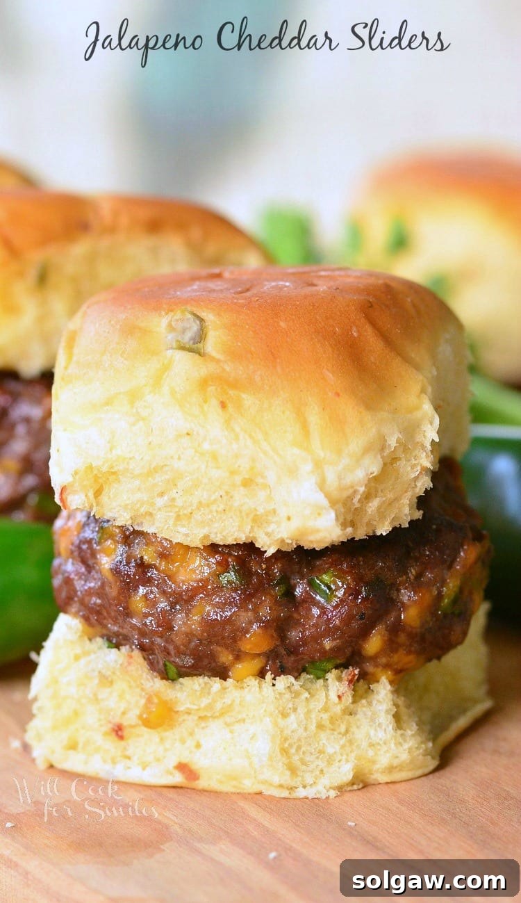 Jalapeno Cheddar Sliders arranged on a rustic wood table, showcasing their cheesy topping.