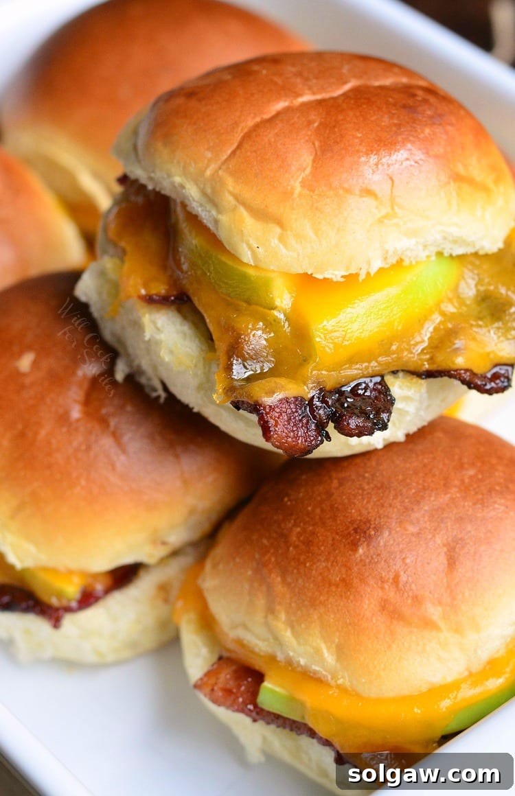 Stacked Apple Bacon Cheddar Baked Sliders within a white baking dish, ready for serving.