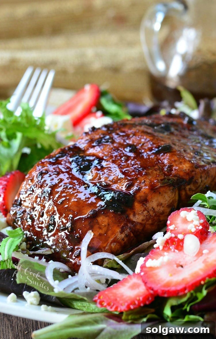 Strawberry Balsamic Glazed Salmon served on a pristine white plate, garnished with fresh herbs.