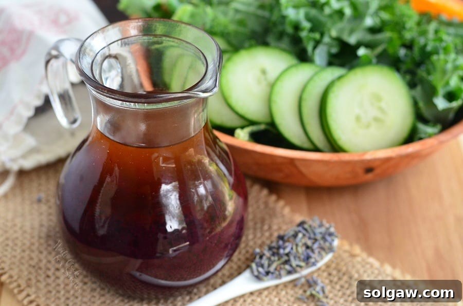 Delicious Blueberry Lavender Vinaigrette in a glass jar, perfectly garnished with fresh lavender, positioned next to a rustic bowl of salad.