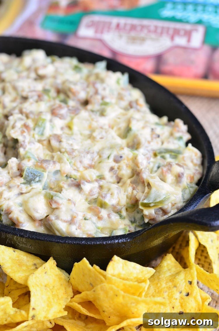 Close-up of creamy Cheesy Sausage Peppers and Onions Dip in a cast iron pan, showing its rich texture and melted cheese before serving