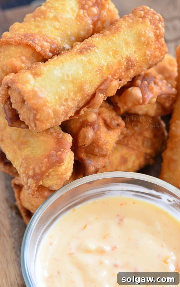 Top view photo of Sweet Chili Chicken Egg Rolls with Creamy Sweet Chili Sauce in a glass bowl on a cutting board