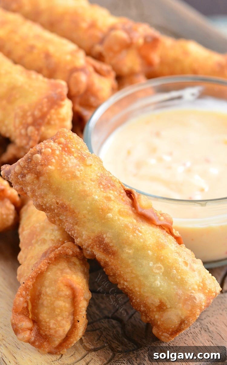 Sweet Chili Chicken Egg Rolls with Creamy Sweet Chili Sauce in a glass bowl on a cutting board