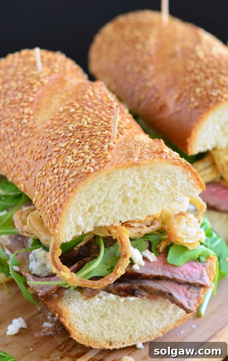 Large, appetizing Steak Sandwich with fresh ingredients and homemade onion rings