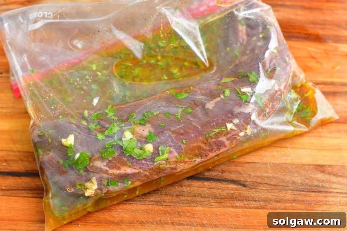 Steak marinating in a clear zip-lock bag, surrounded by the vibrant citrus and herb marinade, ready for grilling to become delicious carne asada tacos.