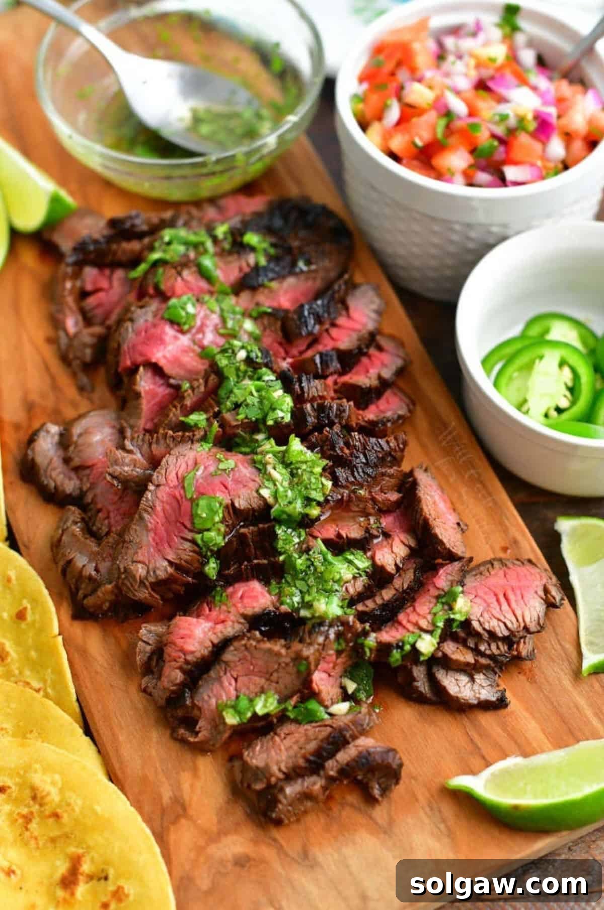 Sliced carne asada steak, drizzled with a fresh herb and citrus vinaigrette, artfully arranged on a wooden cutting board, ready to be added to tacos.