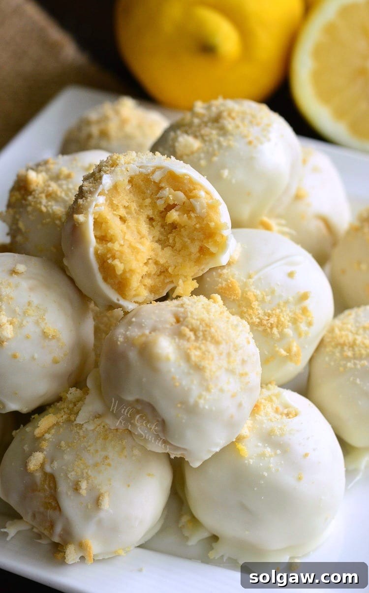 Zesty Coconut Oreo Delights 2 Lemon Oreo Coconut Cookie Truffles on a white plate with a bite taken out of one and lemons in the background