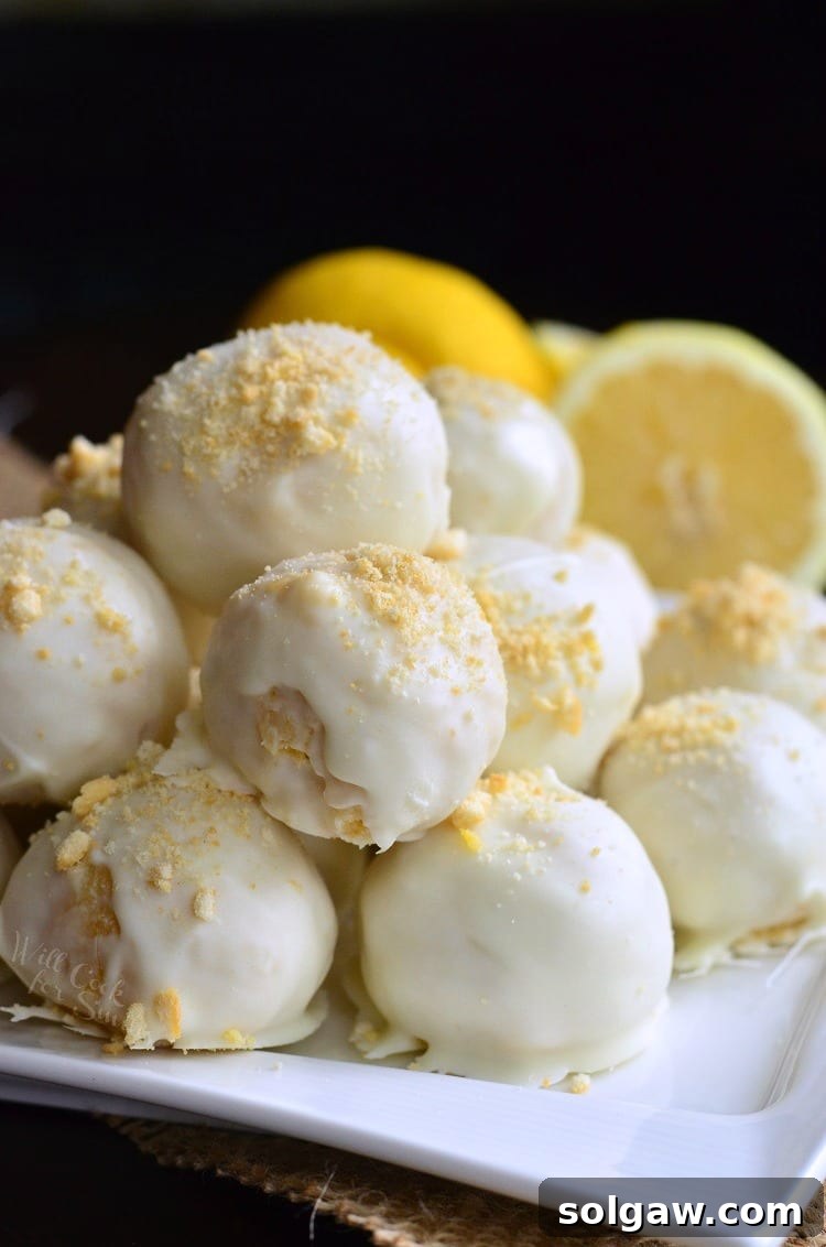 Zesty Coconut Oreo Delights 3 Lemon Oreo Coconut Cookie Truffles stacked up on a white plate with lemons in the background