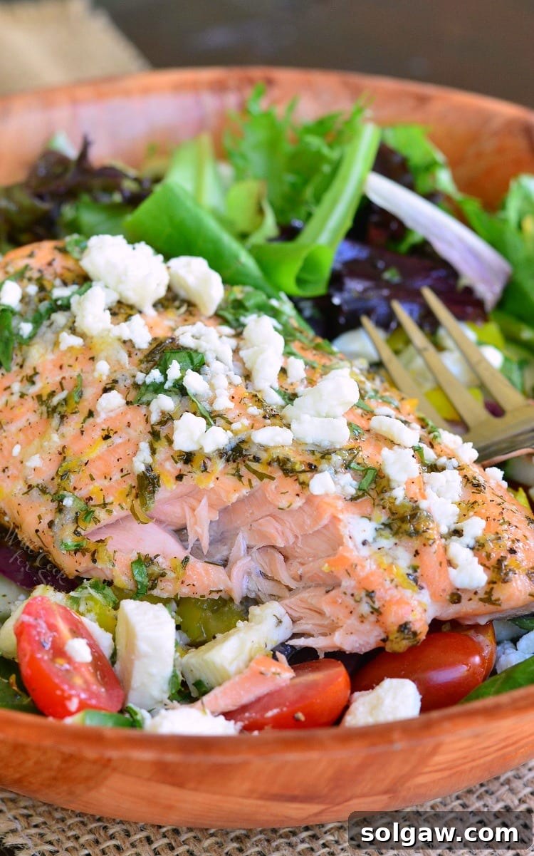 Close-up of Greek Salmon Salad in a rustic wooden bowl with a fork, showing fresh ingredients