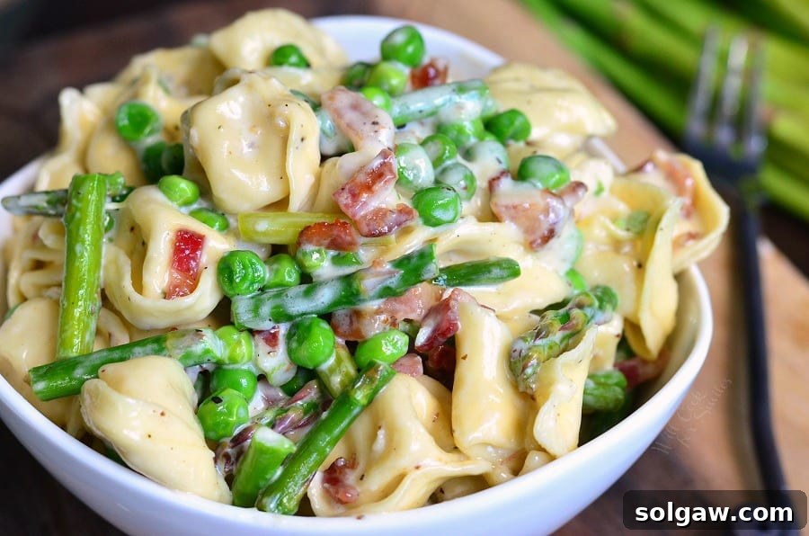 closeup of creamy tortellini with bacon and vegetables.