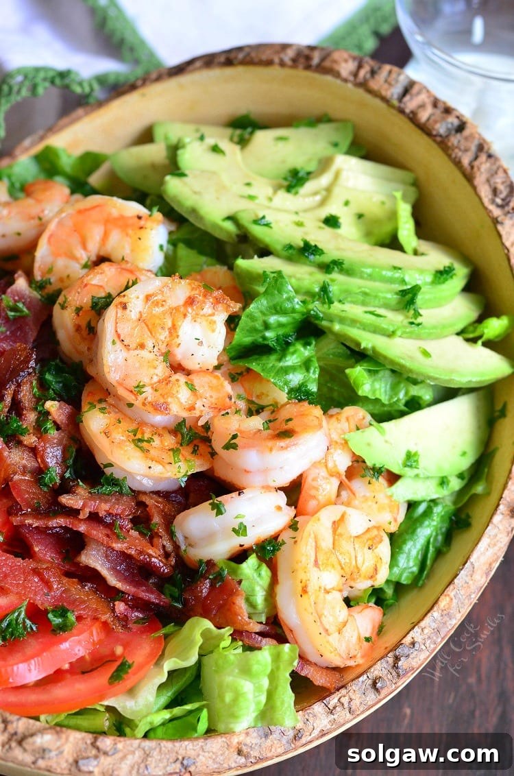 Close-up of a vibrant Shrimp BLTA Salad in a white bowl, showcasing fresh ingredients