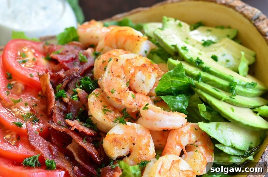 Assortment of fresh ingredients for BLTA salad: tomatoes, crispy bacon, perfectly cooked shrimp, and sliced avocado