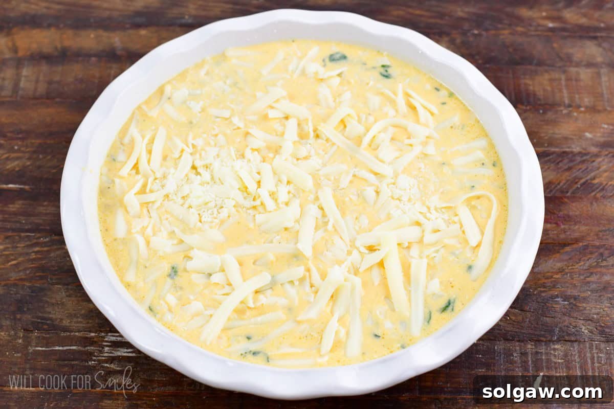 Spinach artichoke crustless quiche mixture in the baking dish, ready to be baked.
