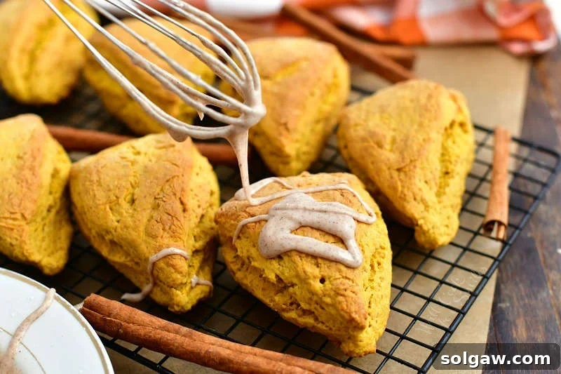 cinnamon glaze dripping from whisk onto a scone