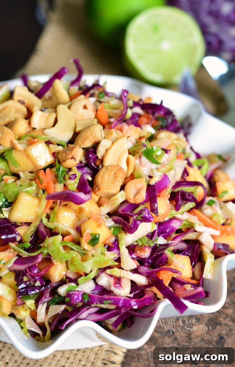 Vibrant Tropical Coleslaw in a white bowl, garnished with a fresh lime.