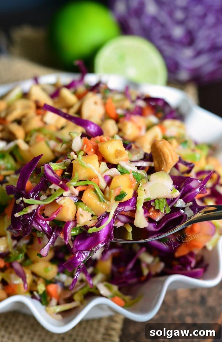 Serving a portion of Tropical Coleslaw from a bowl, highlighting its crisp texture.