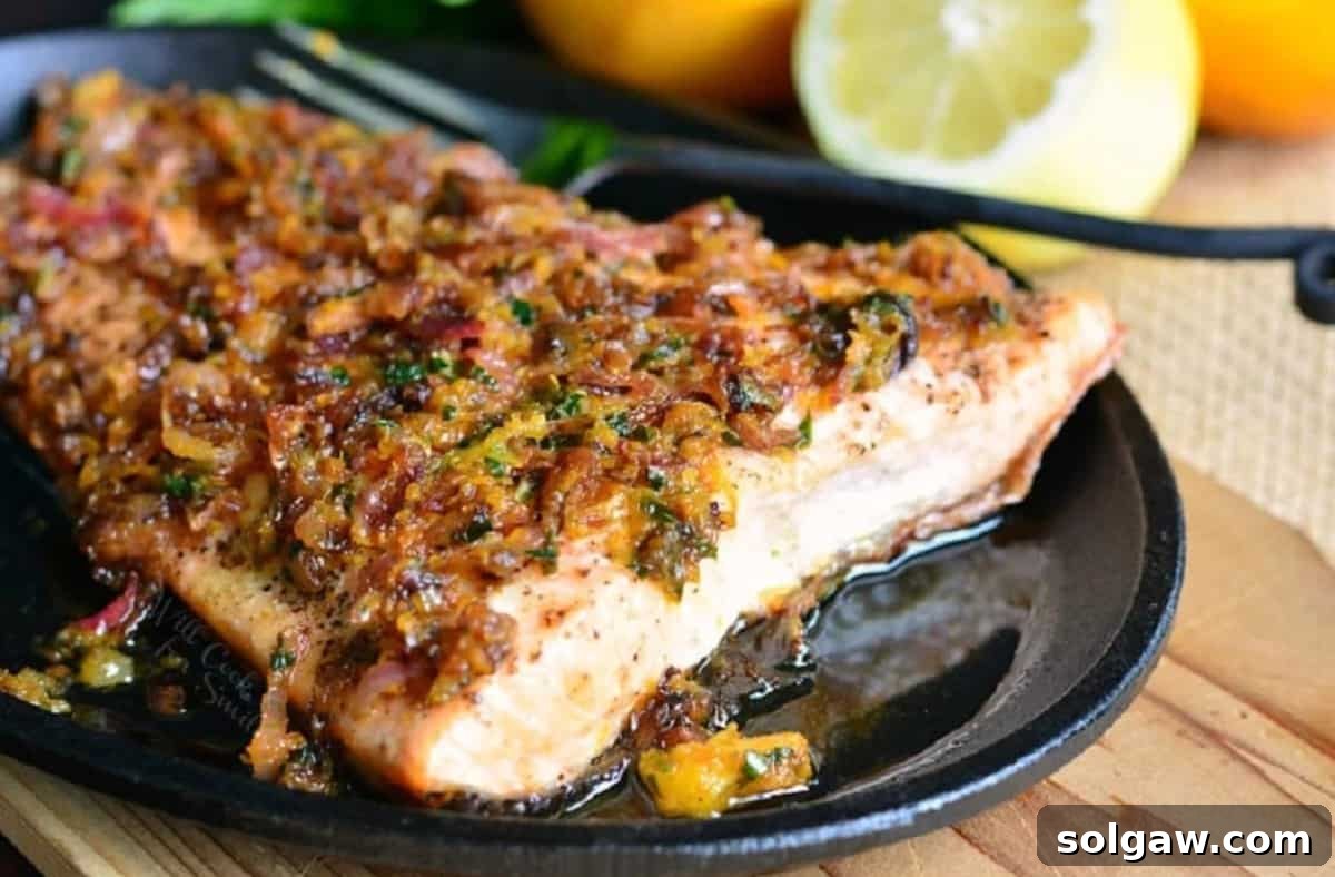 grilled salmon topped with brown butter citrus sauce in a skillet.