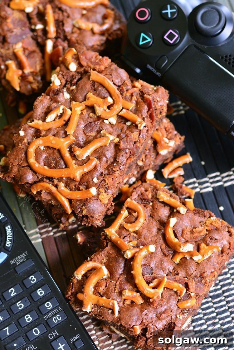 Dad's Brownies aka Pretzel Bacon Brownies on a table with a TV remote and PlayStation remote, highlighting a relaxed setting