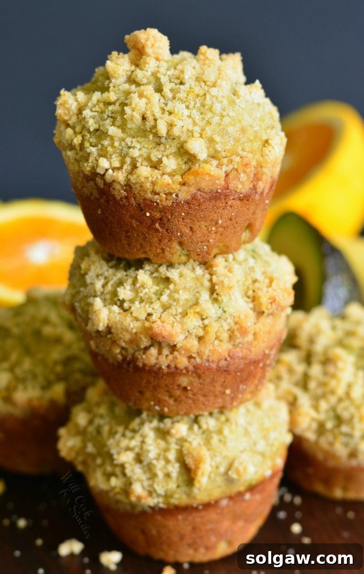 Stacked Avocado Banana Muffins with Orange Streusel on a wooden cutting board, ready to be enjoyed.