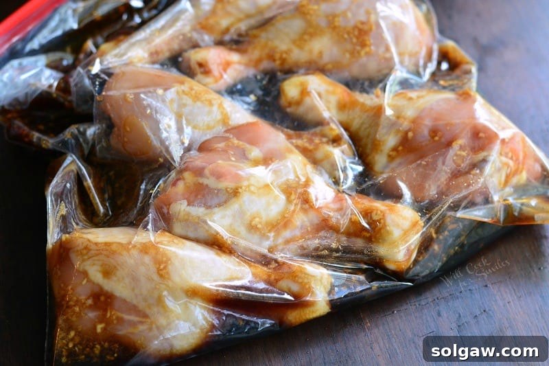Chicken Drumsticks marinating in a clear ziplock bag with a sweet garlic sauce, resting on a clean kitchen surface, ready for grilling.