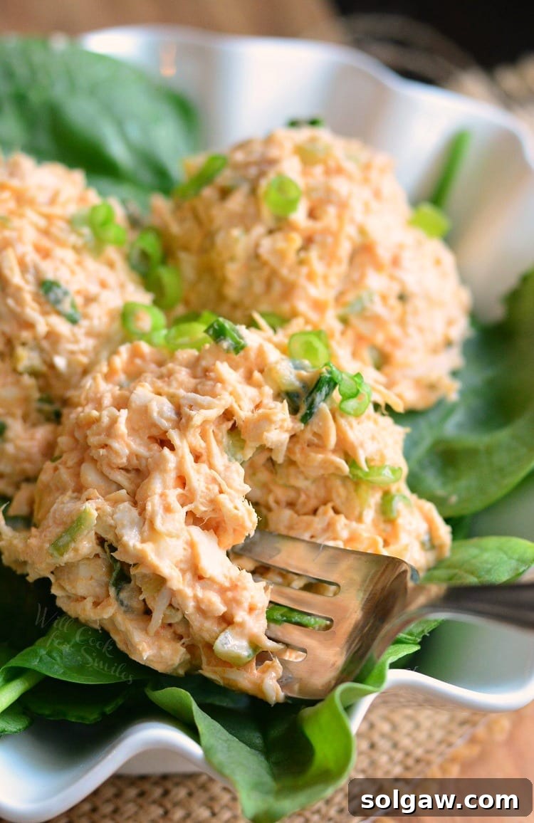 Zesty Buffalo Chicken Salad presented in a white bowl with a fork, emphasizing its fresh ingredients and readiness to eat, against a clean background