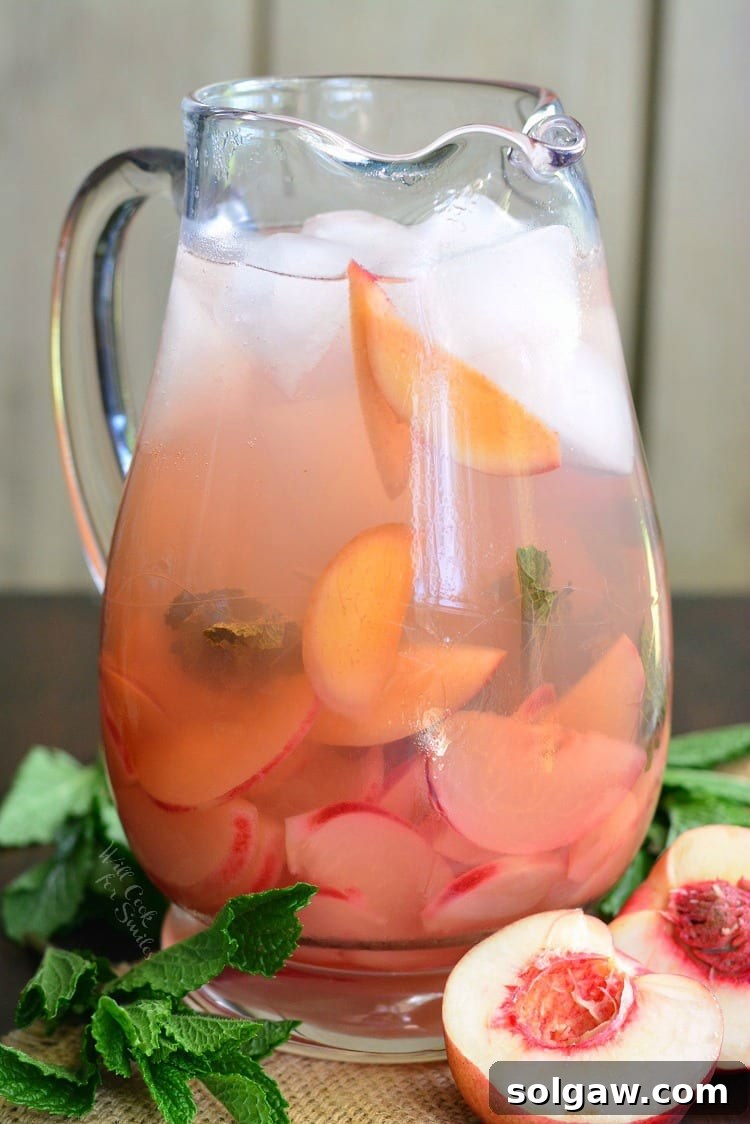 Blushing Peach Rose Mint Sparkler 2 Pitcher filled with fresh mint and sliced peaches, ready for infusing.