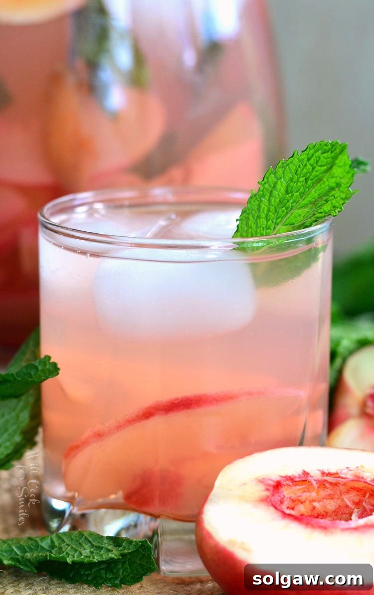 Mint peach spritzer in a glass with a mint leaf as garnish.