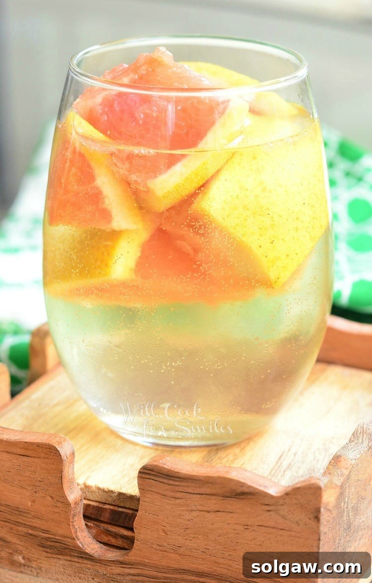 Blushing Peach Rose Mint Sparkler 7 A wine glass filled with vibrant grapefruit sangria, garnished with fresh grapefruit slices.