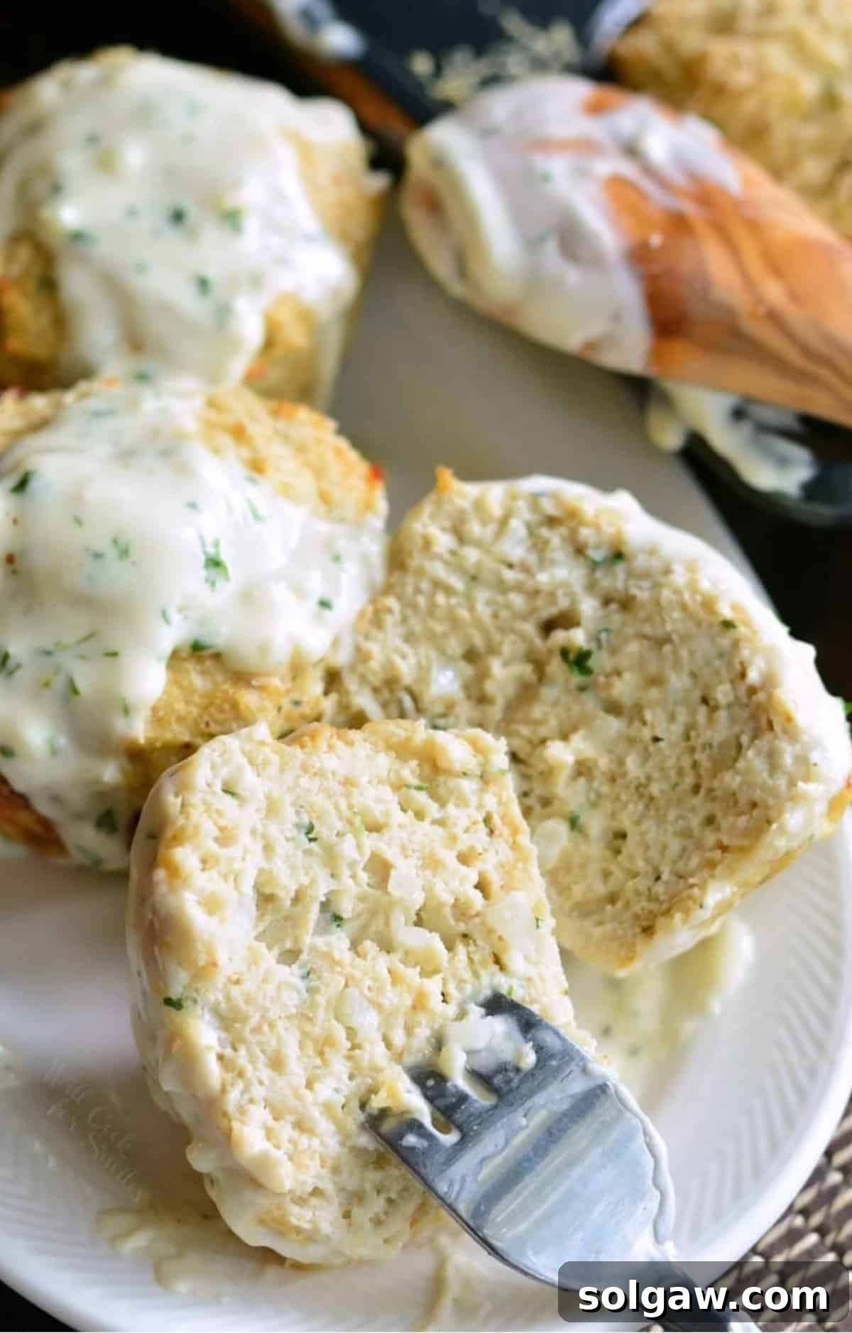 Parmesan Garlic Chicken Mini Loaves 8 A fork is piercing a halved chicken meatloaf on a white plate.
