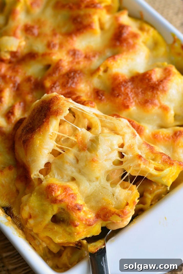 Close-up of Spicy Three Cheese Pumpkin Tortellini Bake in a white casserole dish, showing melted cheese and creamy sauce