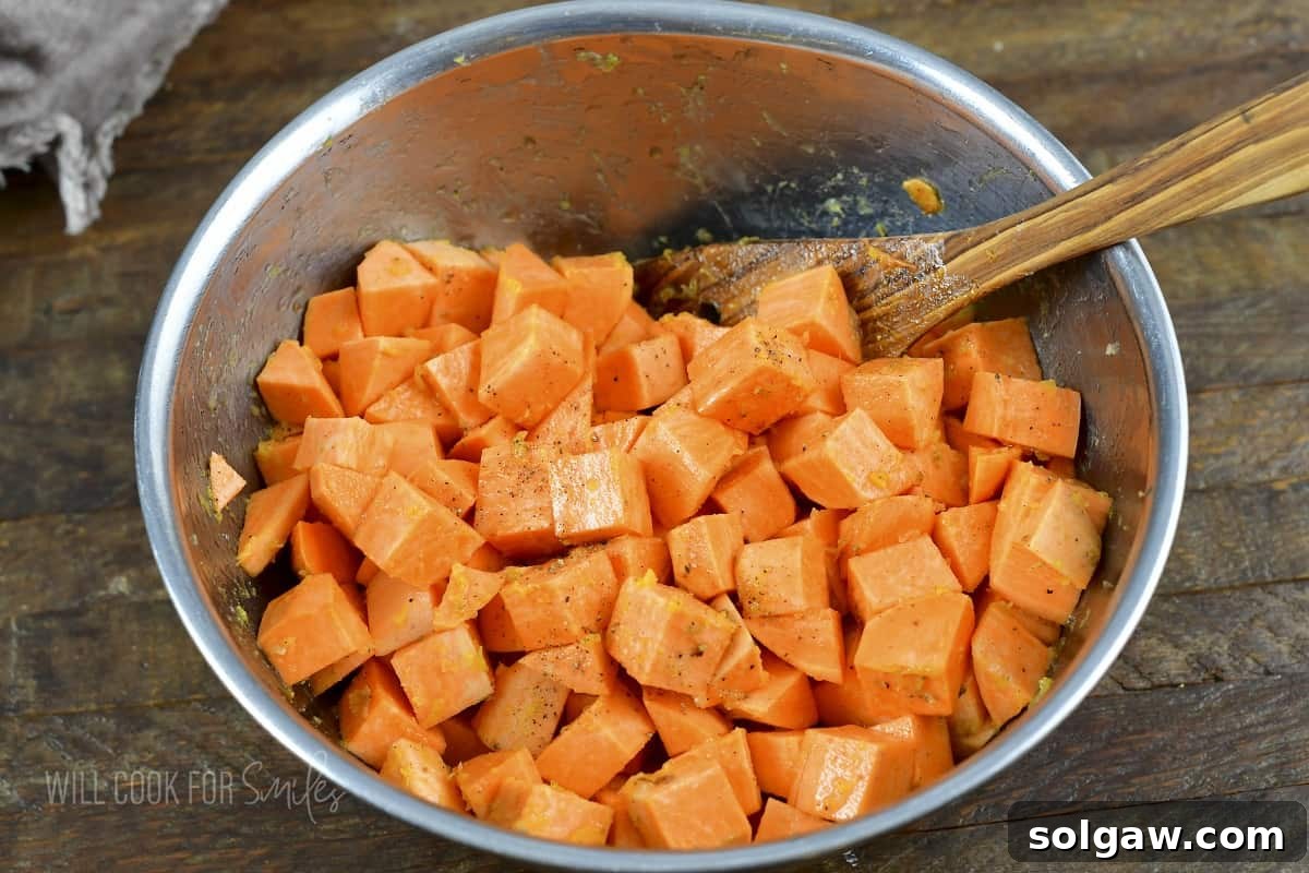 mixing cubed sweet potatoes and seasoning in a bowl.
