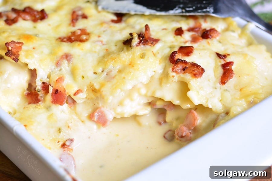 Golden-Baked Ravioli Mac with Crispy Bacon 5 Baked Ravioli Mac and Cheese with Bacon in a white casserole dish with a spatula on top
