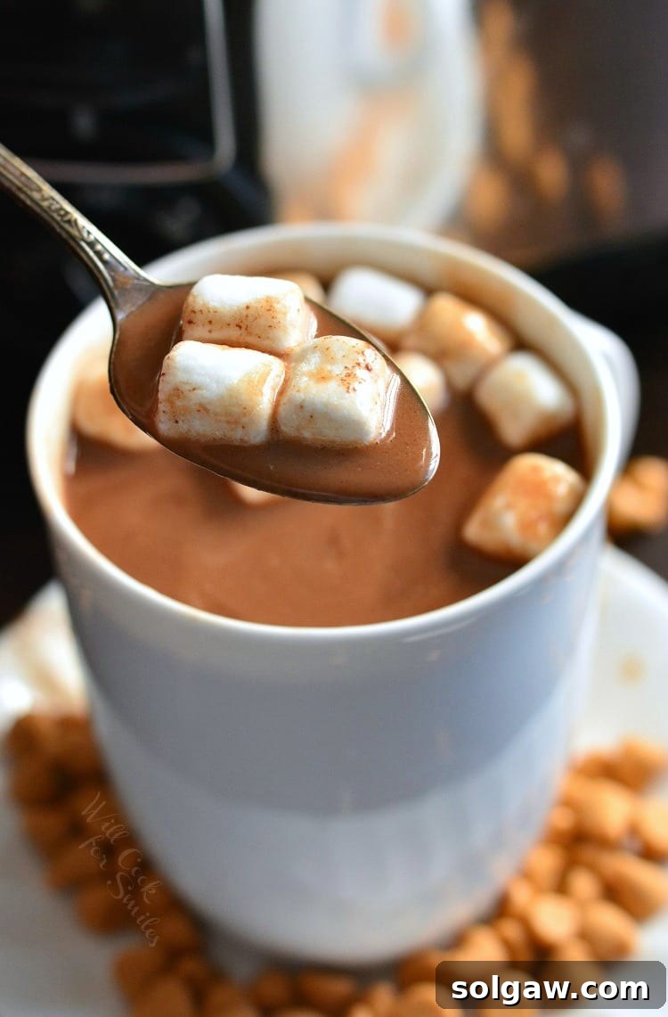 spooning mini marshmallows and some hot chocolate from the mug