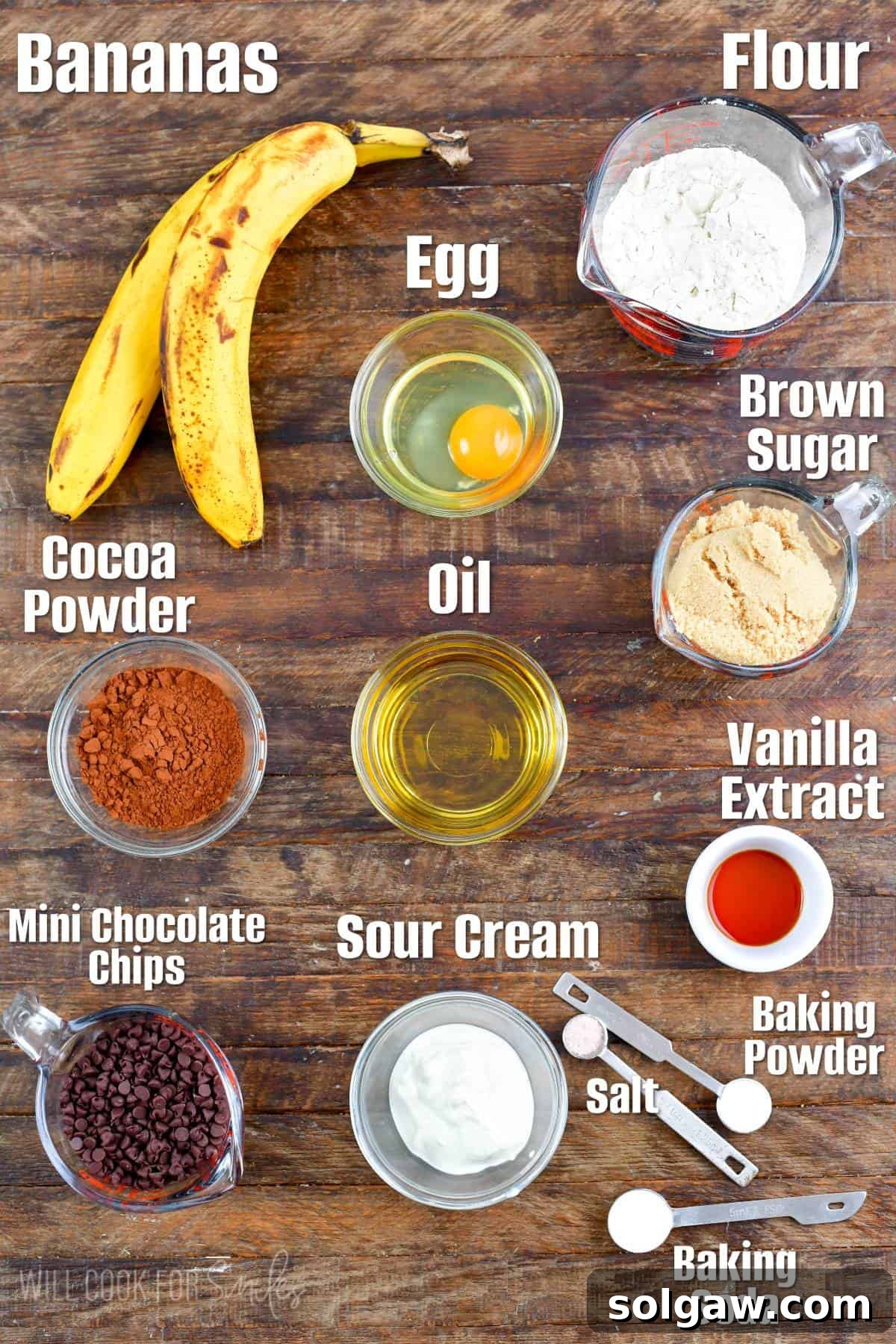 A collection of ingredients for chocolate banana muffins, including ripe bananas, flour, chocolate chips, and cocoa powder, neatly arranged on a wooden board.