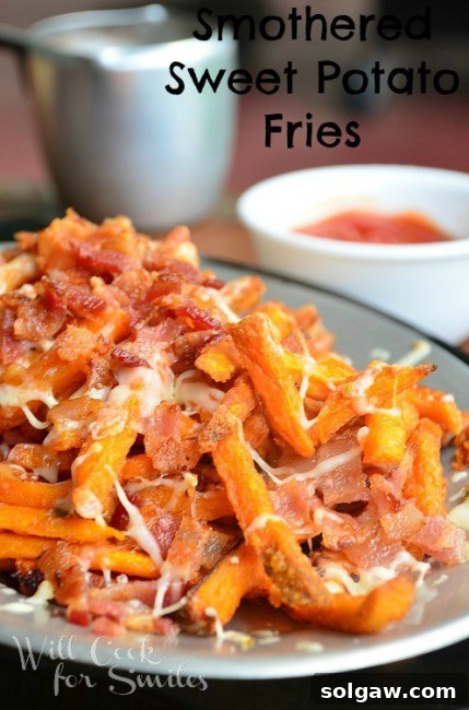 Close-up view of a serving of smothered sweet potato fries, highlighting the rich melted cheese, crispy bacon, and golden-baked fries, with a tantalizing sheen