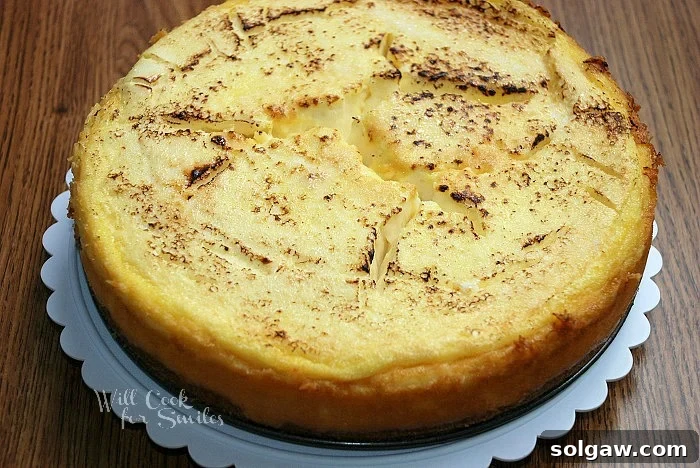 The finished Crème Brûlée Layered Cheesecake displayed on an elegant cake stand, showcasing its beautiful layers and golden caramelized top.